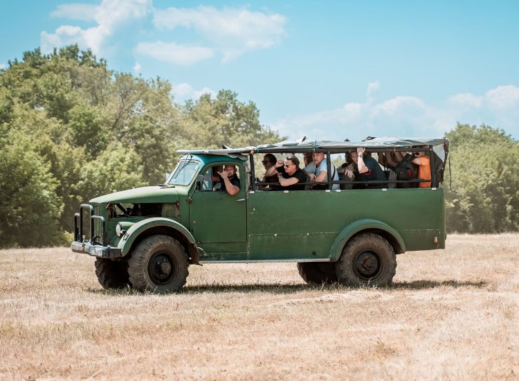 A green tourist jeep with a group of people traveling outdoors.