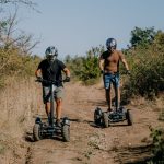 Footage of men riding electric scooters on a mountain trail.