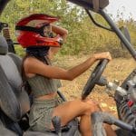 летяща жена с каска управлява офроуд кола в природата.
