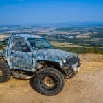 стар бял джип с големи off-road гуми в планински пейзаж България.