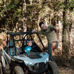 Въоръжен с каска и усмивка, млад водач кара ATV в природния парк Хилвю България.